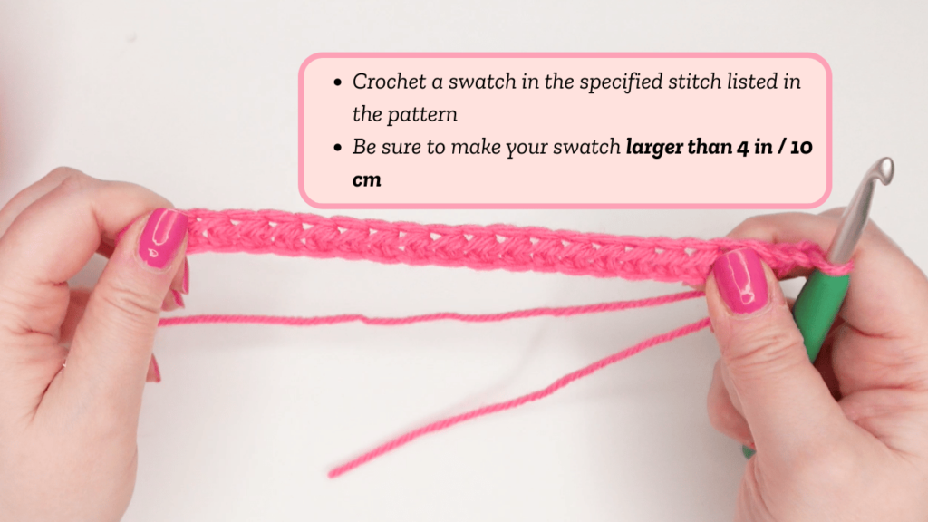Crocheter holding a pink yarn starting chain with green crochet hook