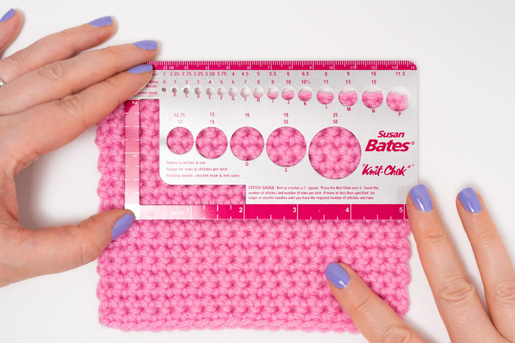 woman measuring crochet gauge with a susan bates knit check