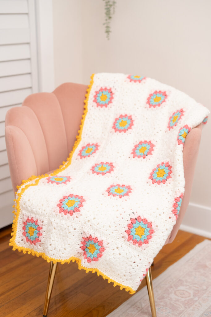 image of the Raspberry Sprinkle Granny Square Blanket draped over a pink chair
