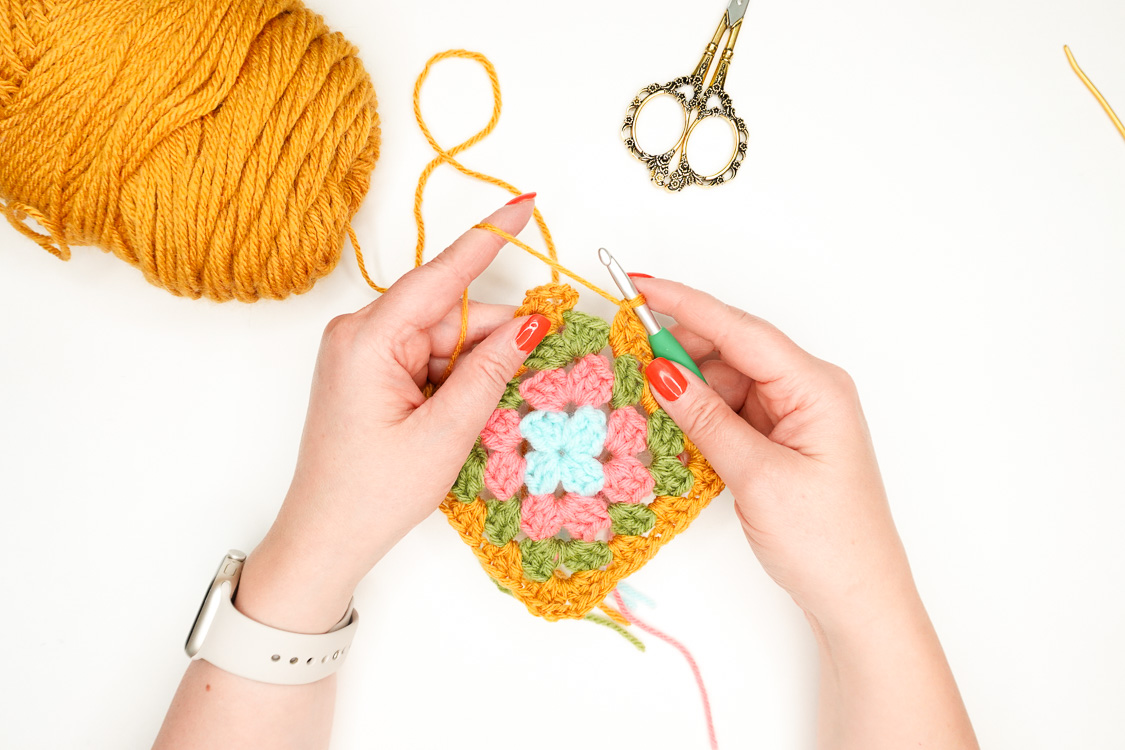 woman crocheting a granny square