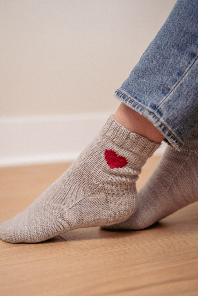 Handmade pink knitted socks with a heart motif – perfect for lounging at home.