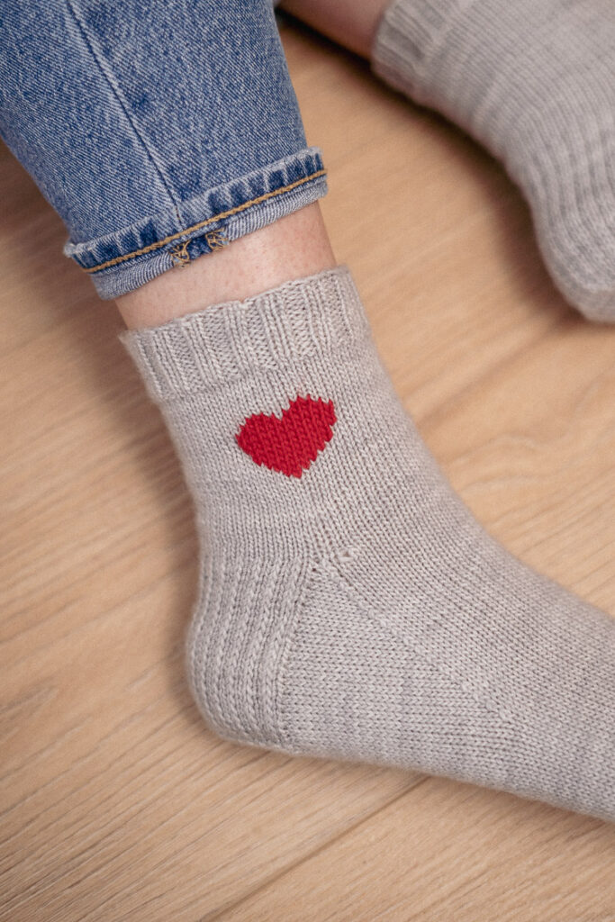 Close-up of a cozy knit heart sock on a foot, highlighting the soft yarn and pattern details.