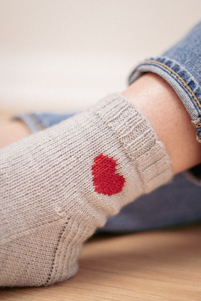 Knit heart socks on bare feet, showing the intricate pattern and cozy fit.