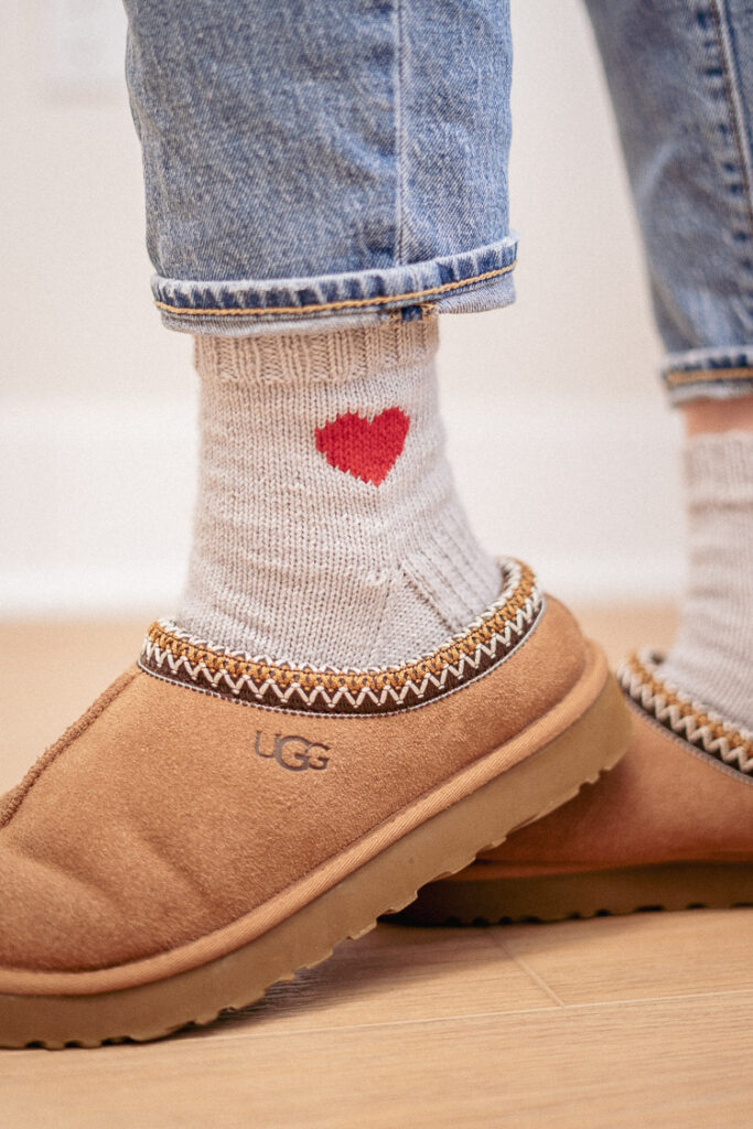 Hand-knit heart socks peeking out from cozy slippers – the perfect Valentine’s Day project!