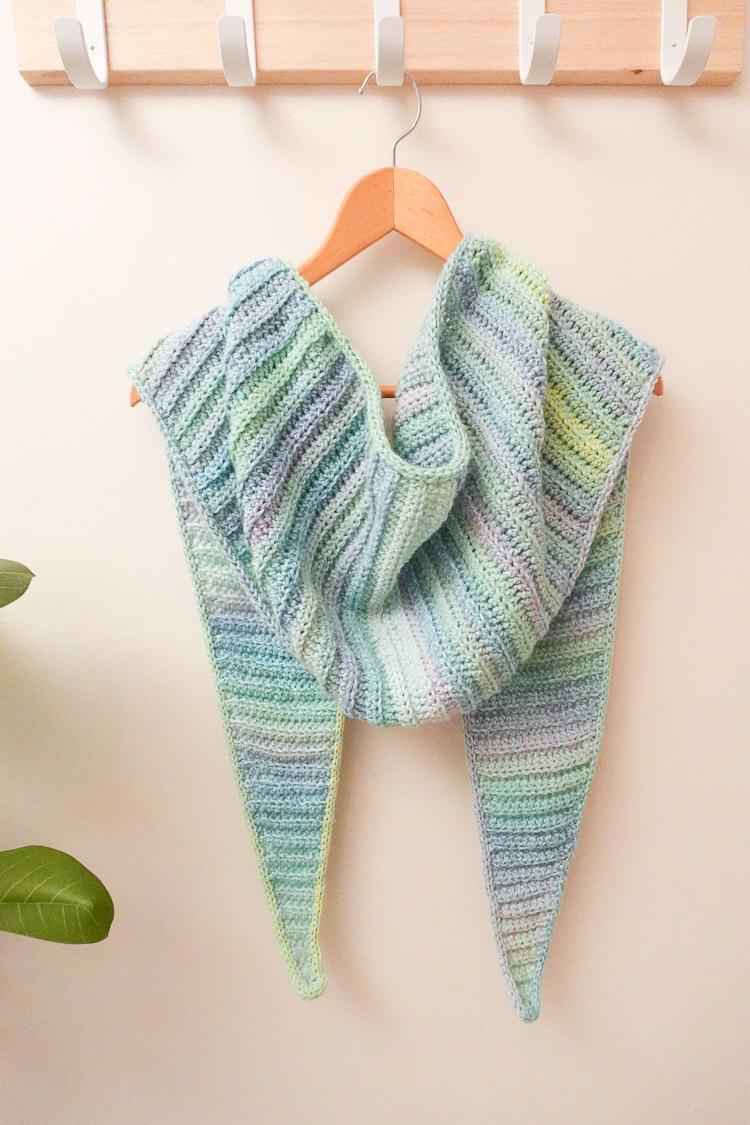 The Watercolor Shawl hanging from a hanger on a hook