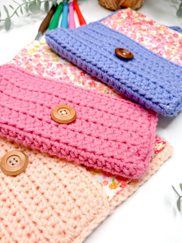 flat lay of fabric lined crochet case holder in three colors, pink, periwinkle and peach