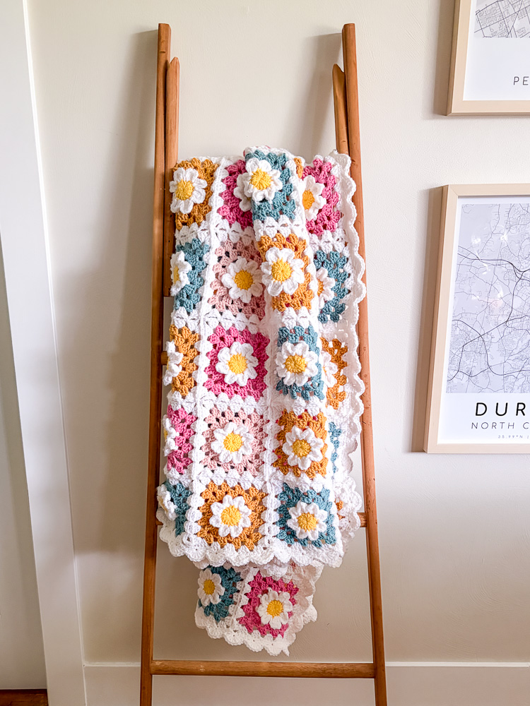 flower granny square blanket hanging over a ladder against a wall